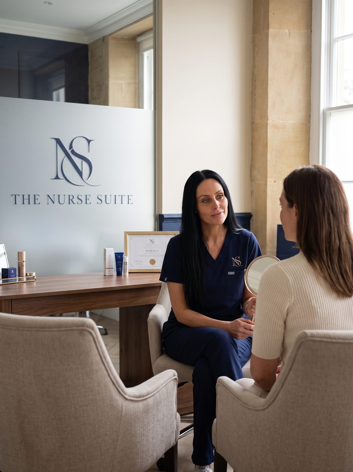 Danielle in conversation with a client during a consultation, hand mirror in hand